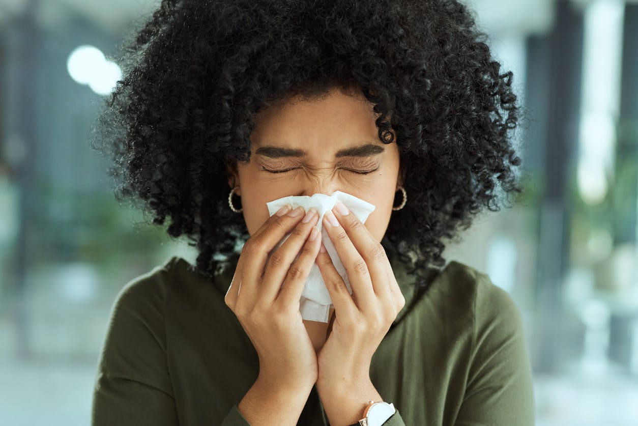 Woman blowing her nose at work