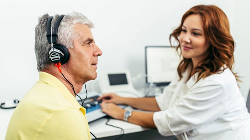 a doctor testing a patients hearing with headphones