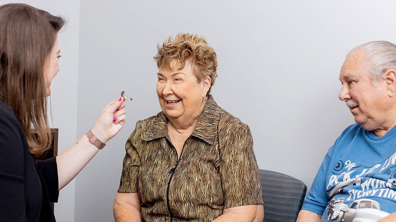 an image of a doctor showing an older patient a hearing aid