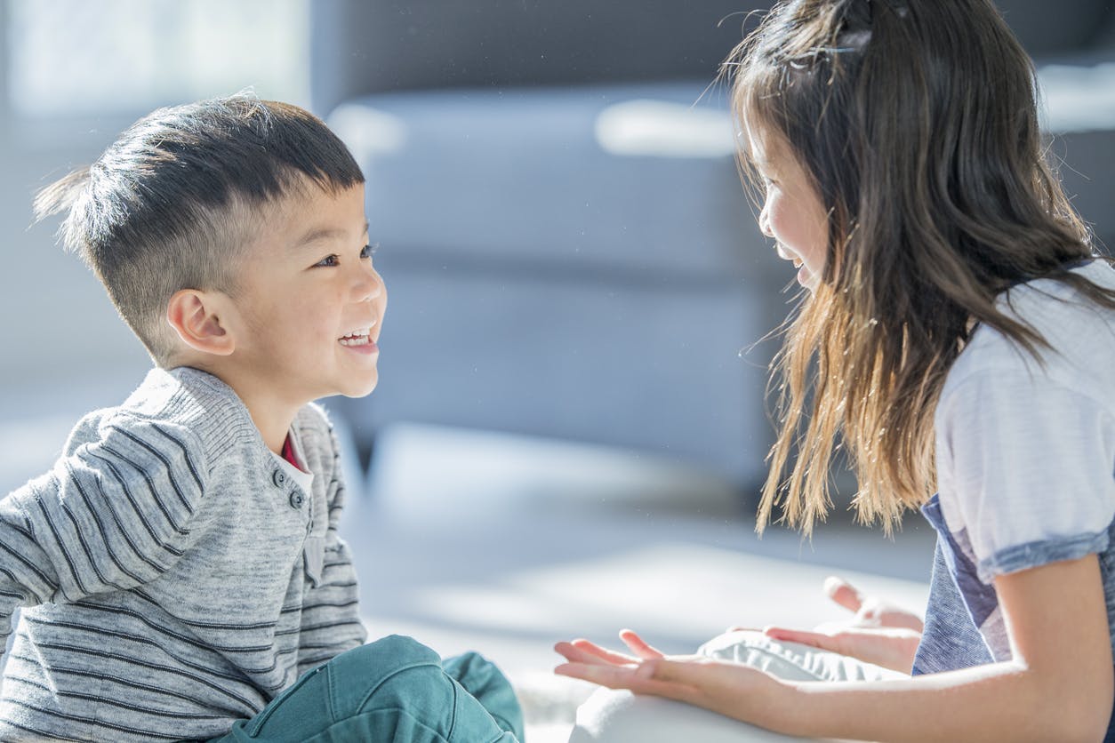 Two asian children smiling and talking