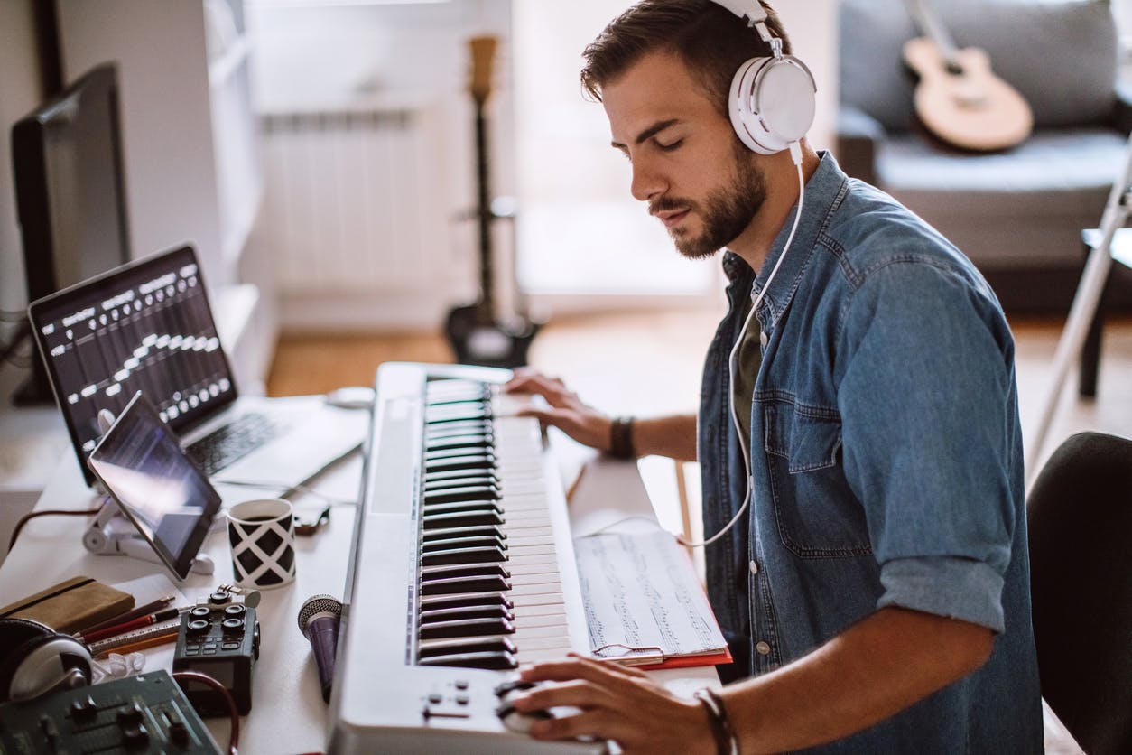 Male musician arranging music on a keyboard