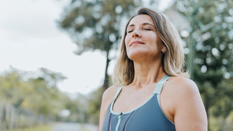 a woman in a blue tank top taking a deep breath