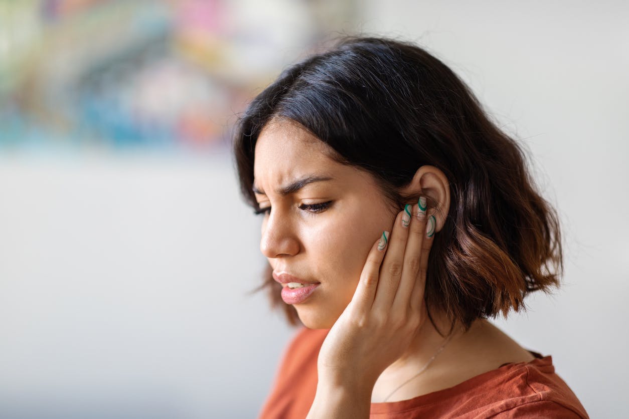 Woman holding her ear because of ear pain