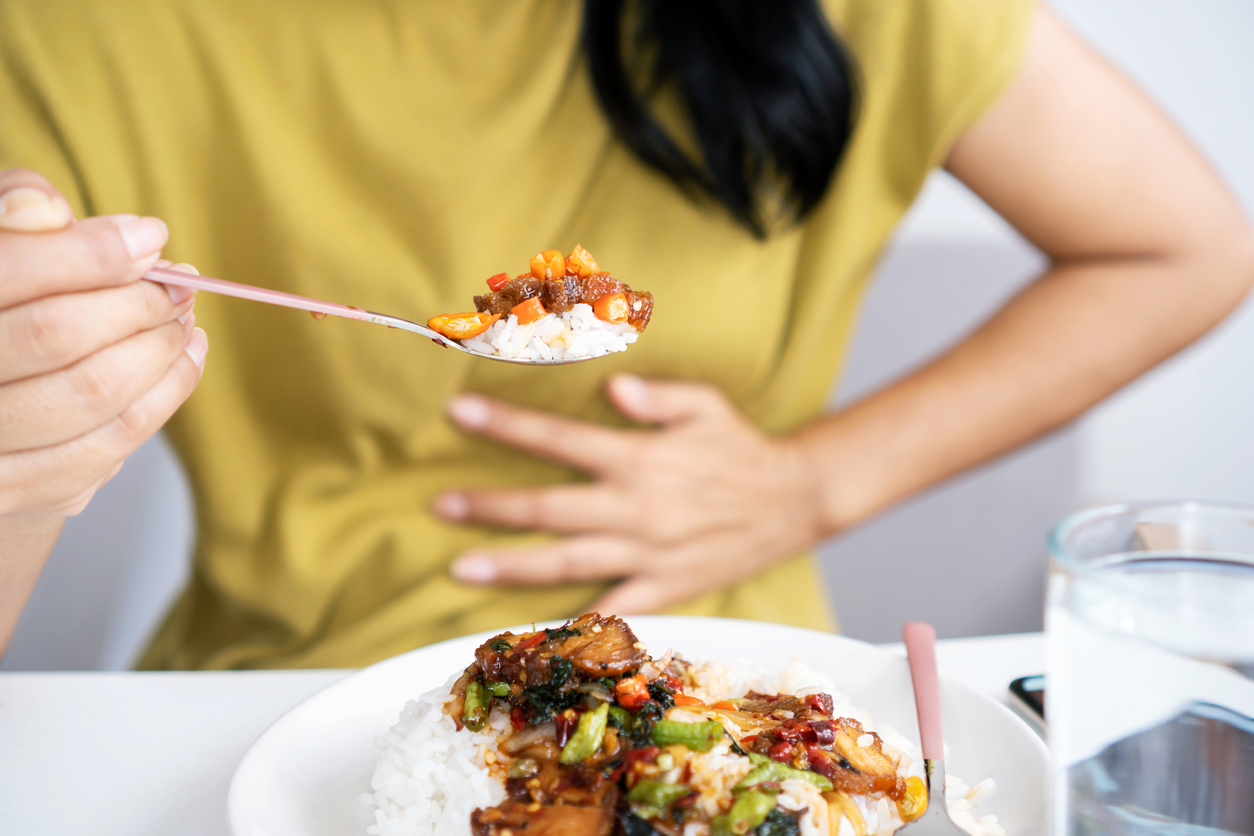 Woman holding her stomach while eating spicy food