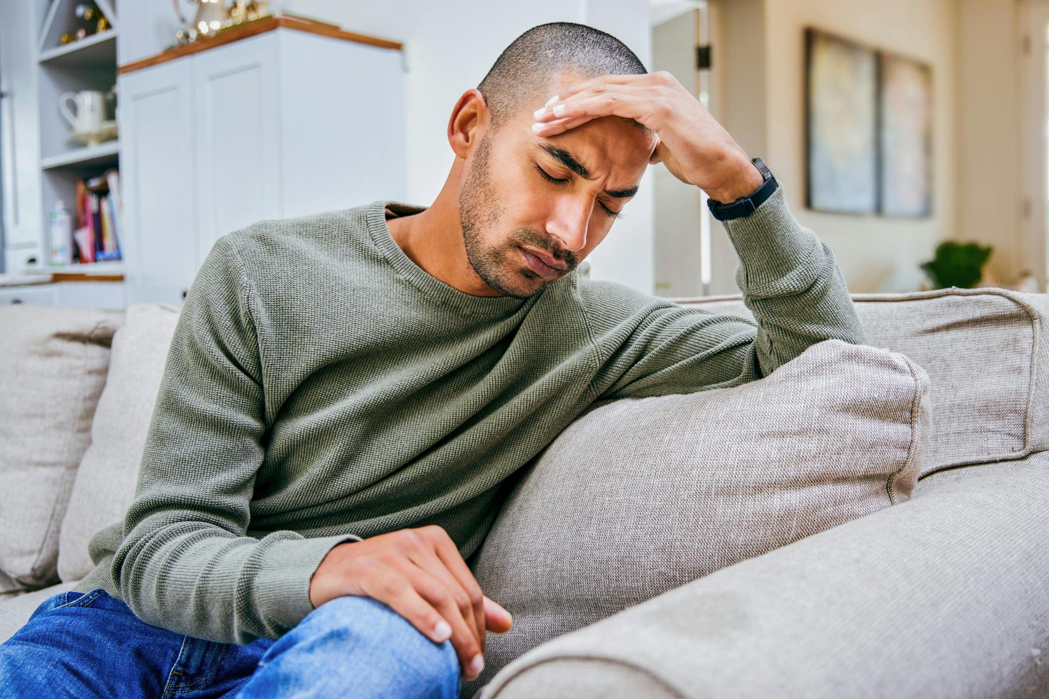 Man sitting on couch with headache