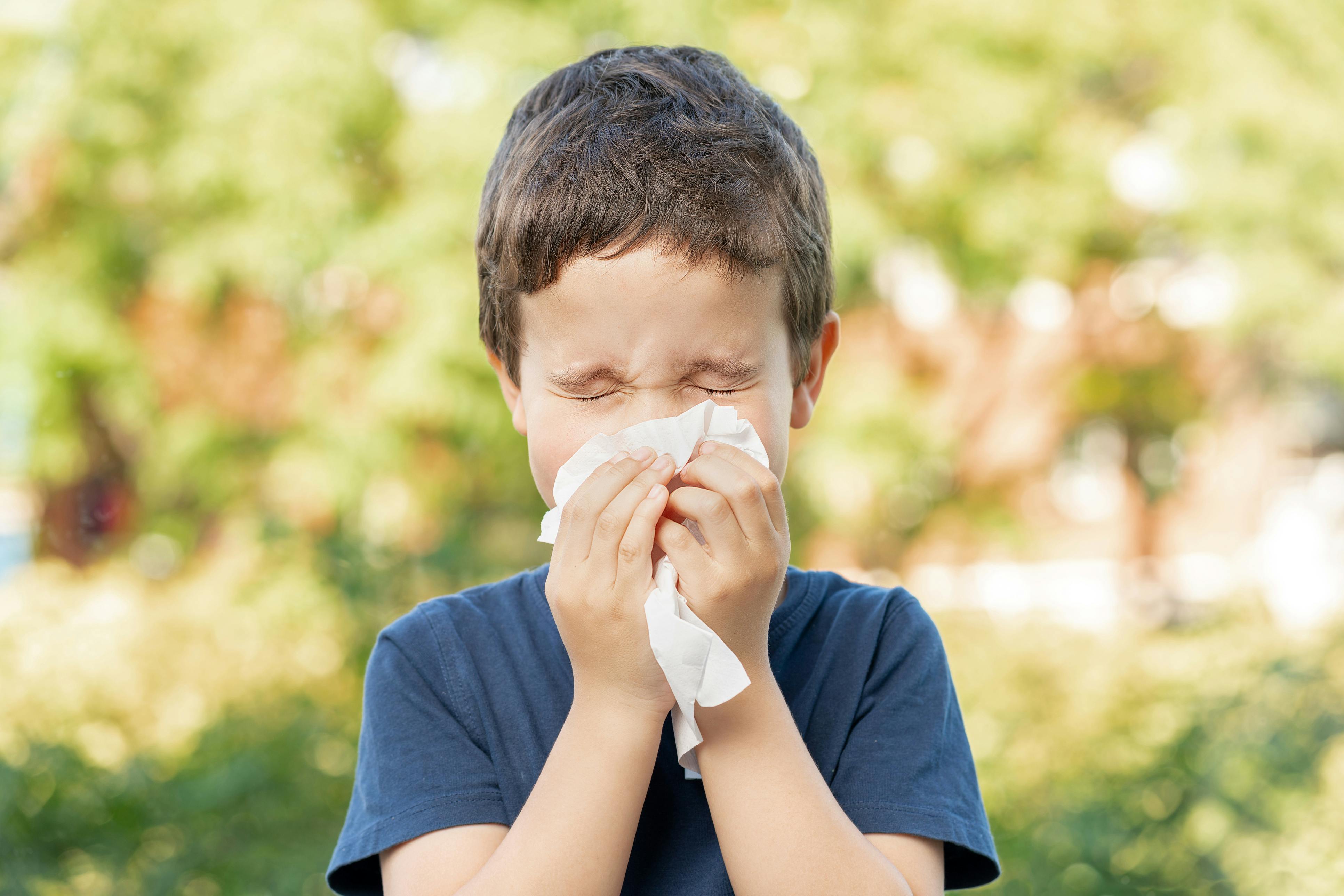 Child sneezing into a tissue outside