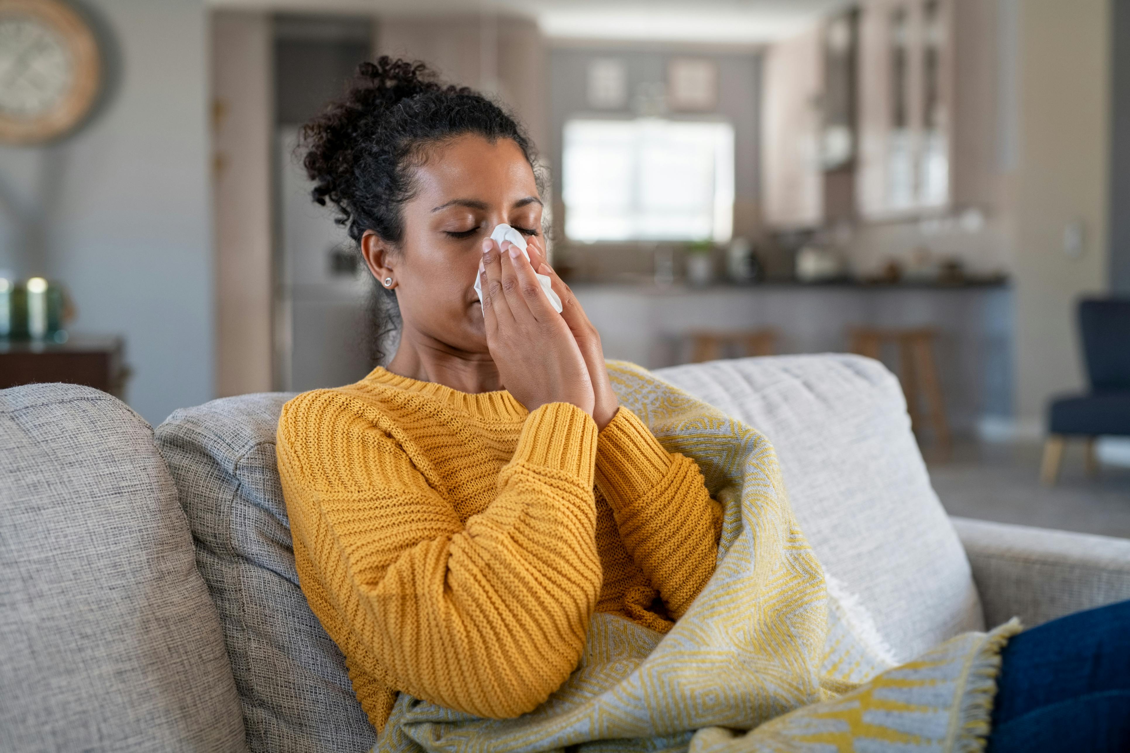 Woman in yellow sweater blowing their nose