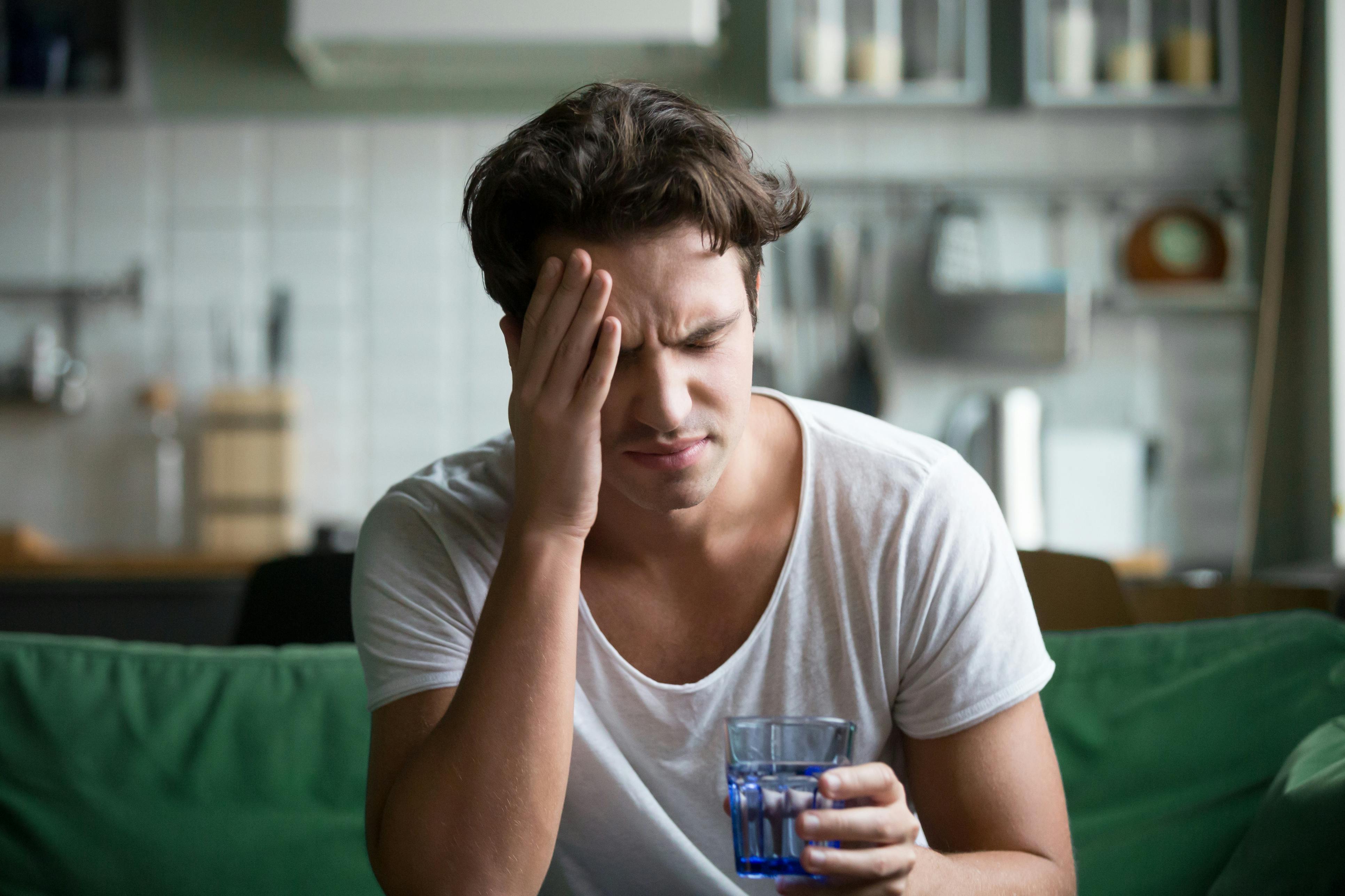 man with headache sitting on couch