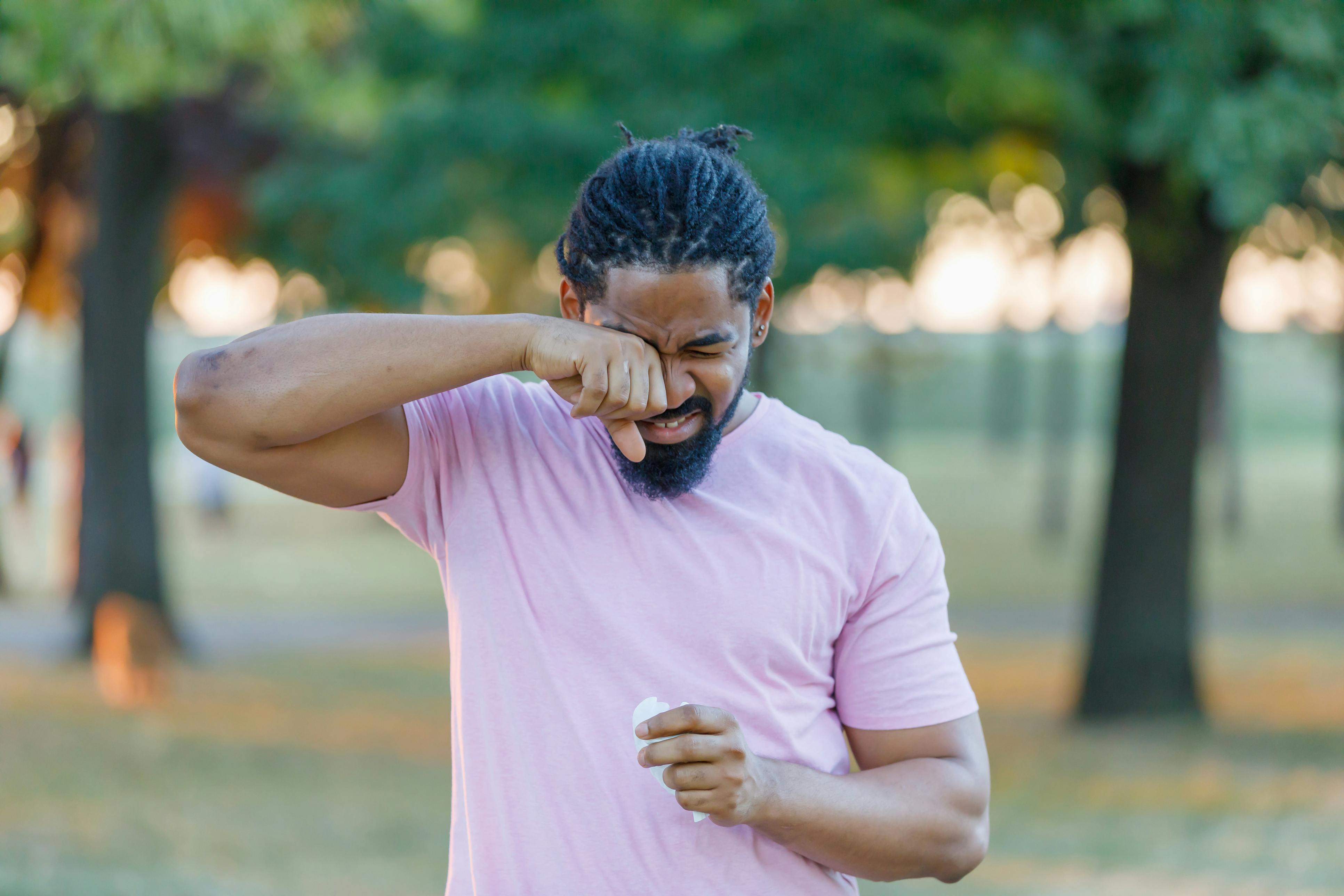 man wiping his nose outside