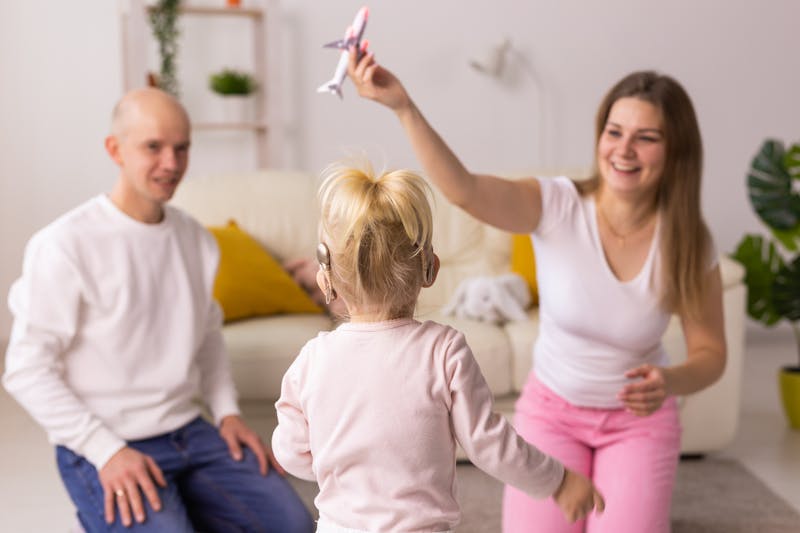 mom and dad playing with child who has cochlear implants