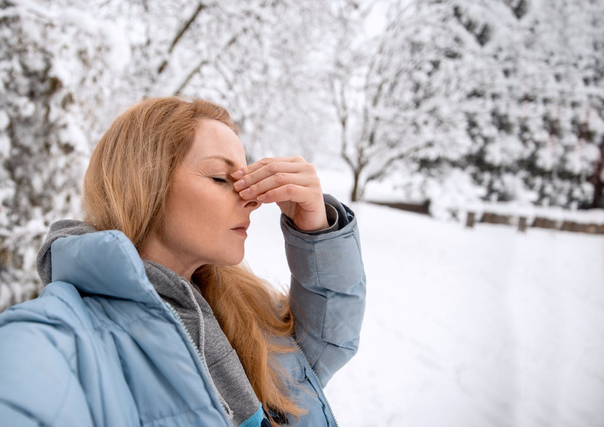 woman holding on to bridge of her nose