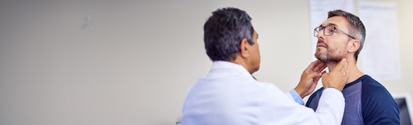 Doctor inspecting man's throat