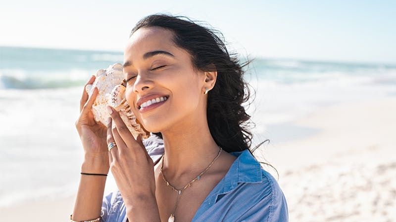 Beautiful latin woman hearing the sound of the sea