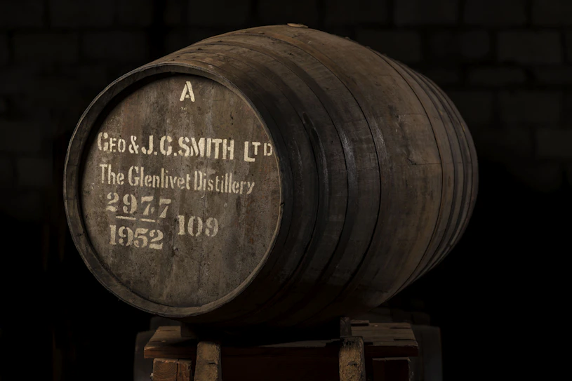 Een zeldzaam whiskyvat uit 1952 van The Glenlivet Distillery, beheerd door Gordon & MacPhail, rustend in een donkere opslagruimte. Dit historische vat symboliseert de essentie van langetermijn whiskybelegging: geduld, schaarste en potentieel voor waardegroei.