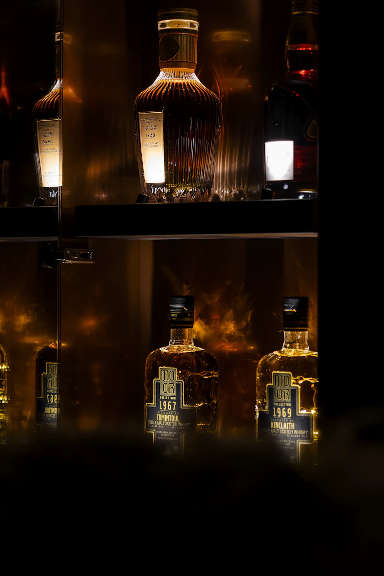 Verlichte vitrinekast in The Unprecedented met zeldzame Moor Collection whiskyflessen, waaronder Tomintoul 1967 en Kinclaith 1969, in het Botanic Sanctuary Antwerp.