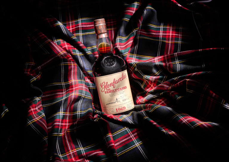 Een fles Glenfarclas Family Casks 1969 single cask Highland malt Schotse whisky, gebotteld in 2007, liggend op een traditionele rood-groene Schotse ruit doek.