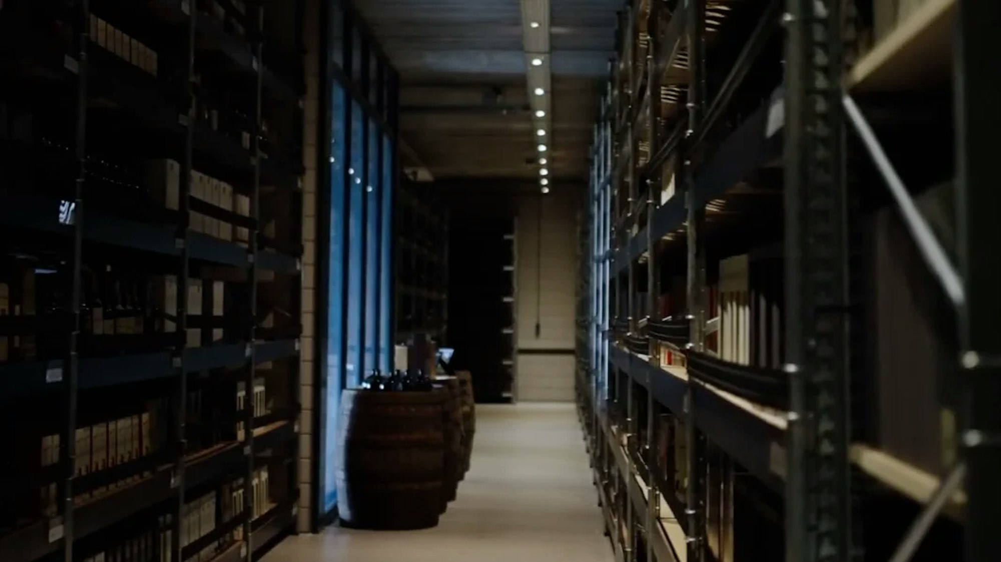 An aisle of shelving filled with bottles in a secured vault
