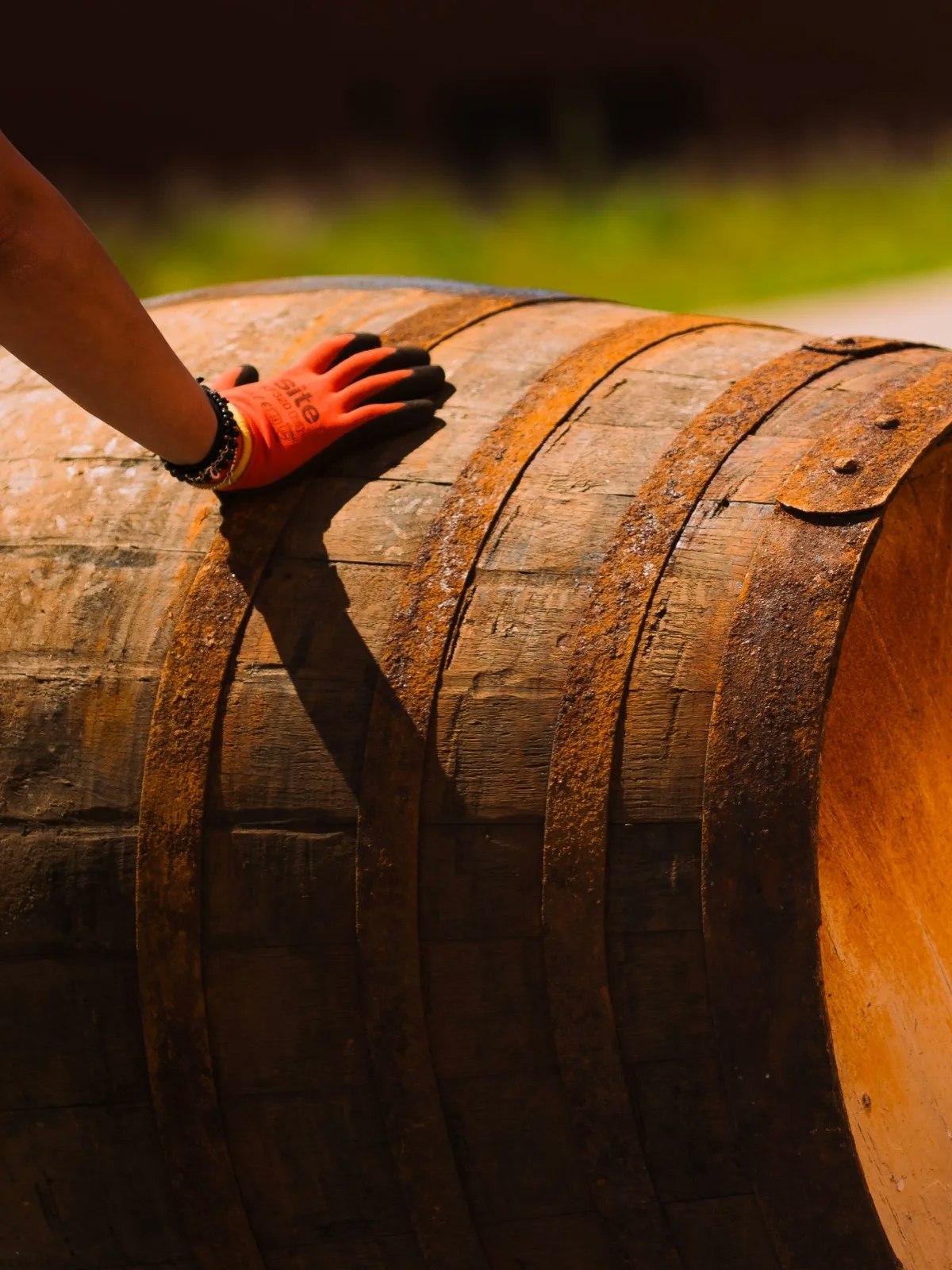 A gloved hand resting on the head of a whisky cask