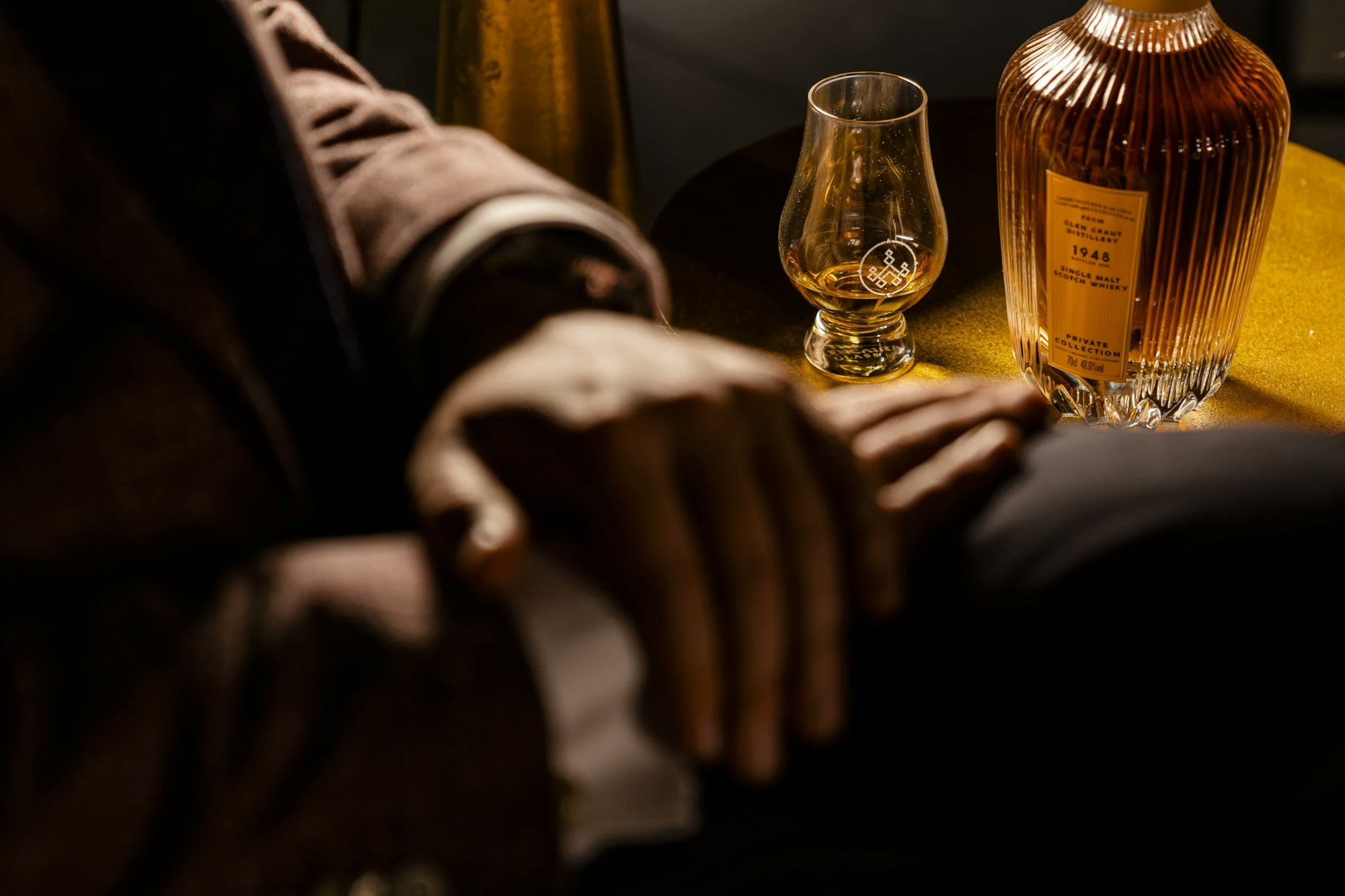 Een whiskyglas en een karaf naast elkaar in gedempt licht