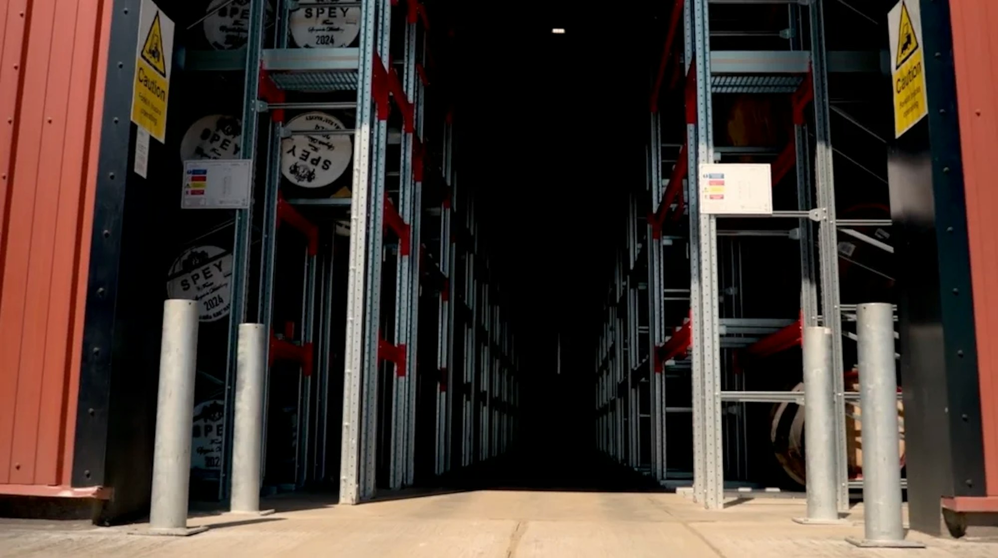 Gangpad tussen hoge stellingen met whiskyvaten in een warehouse