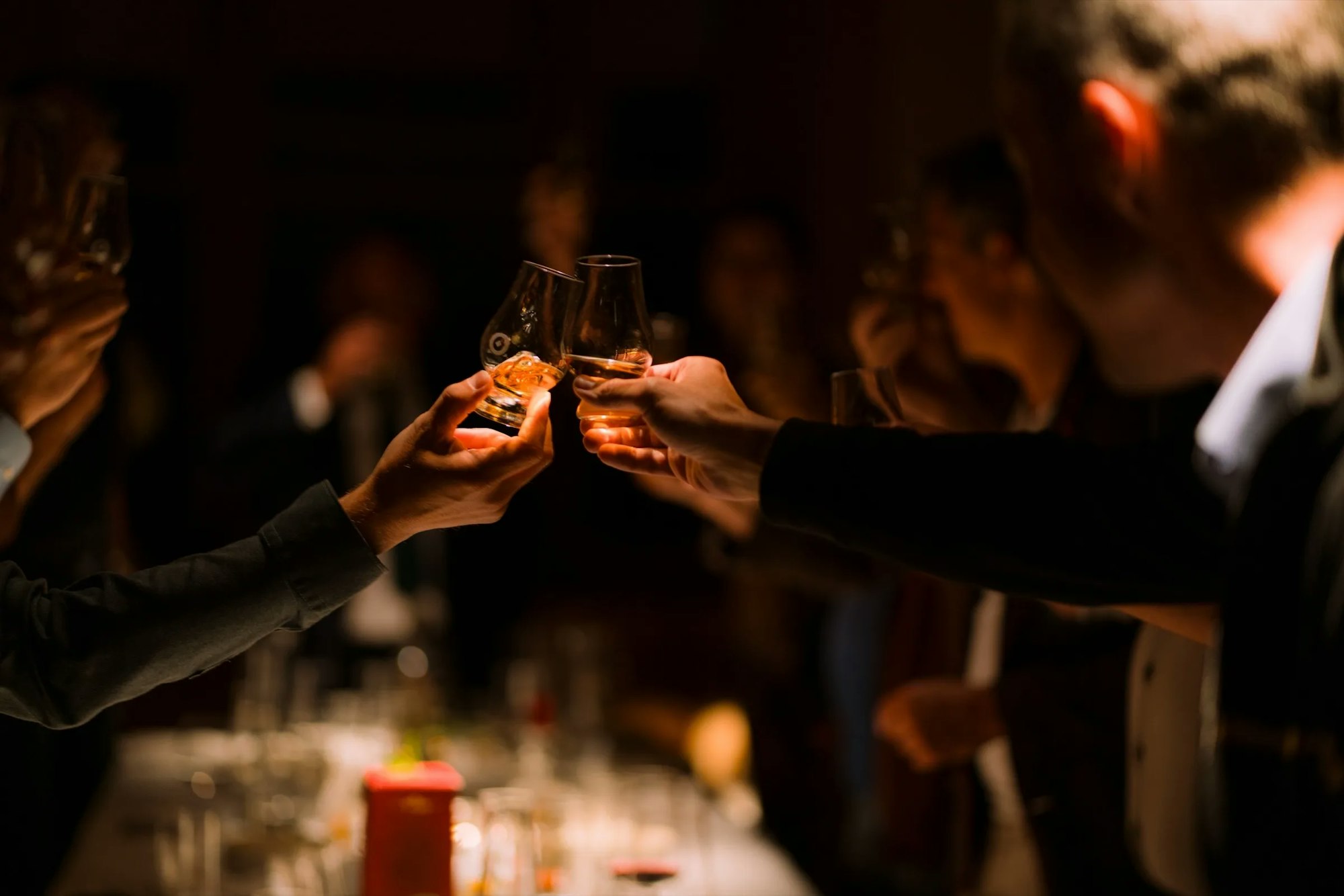 Two whisky glasses being toasted together at an event