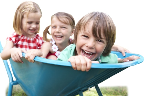 3 kids in wheelbarrow laughing and smiling at camera