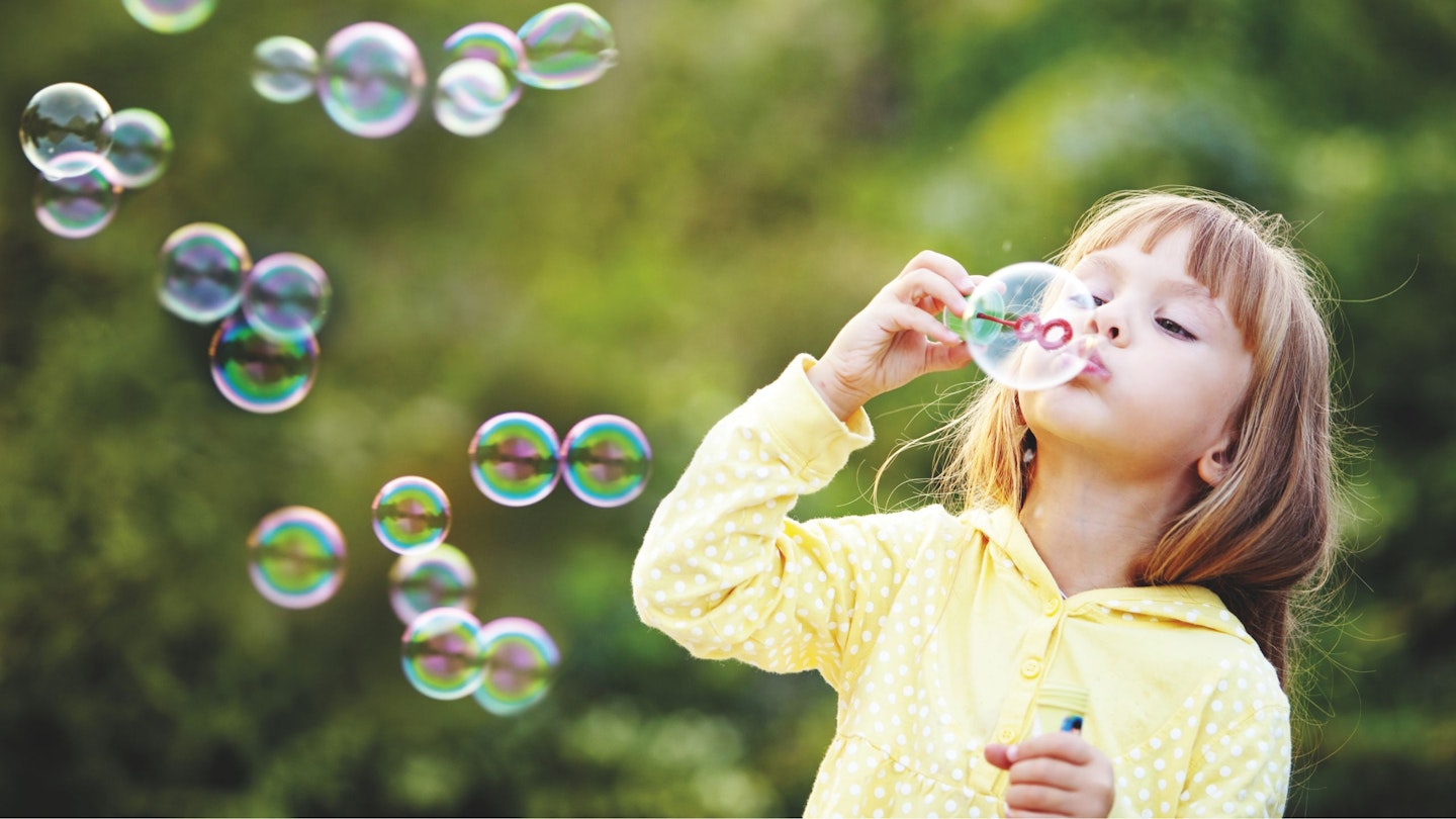Young girl blowing a bubble outside