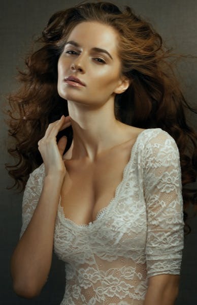 Model wearing white top and touching her neck