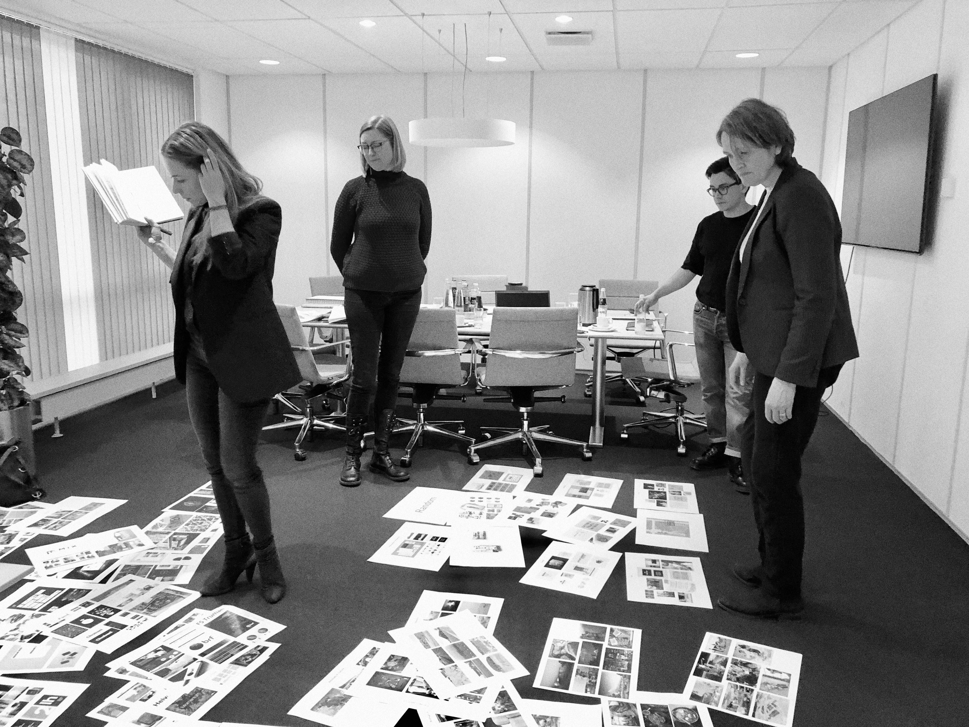 Black and white picture of office with papers on floor and four people working