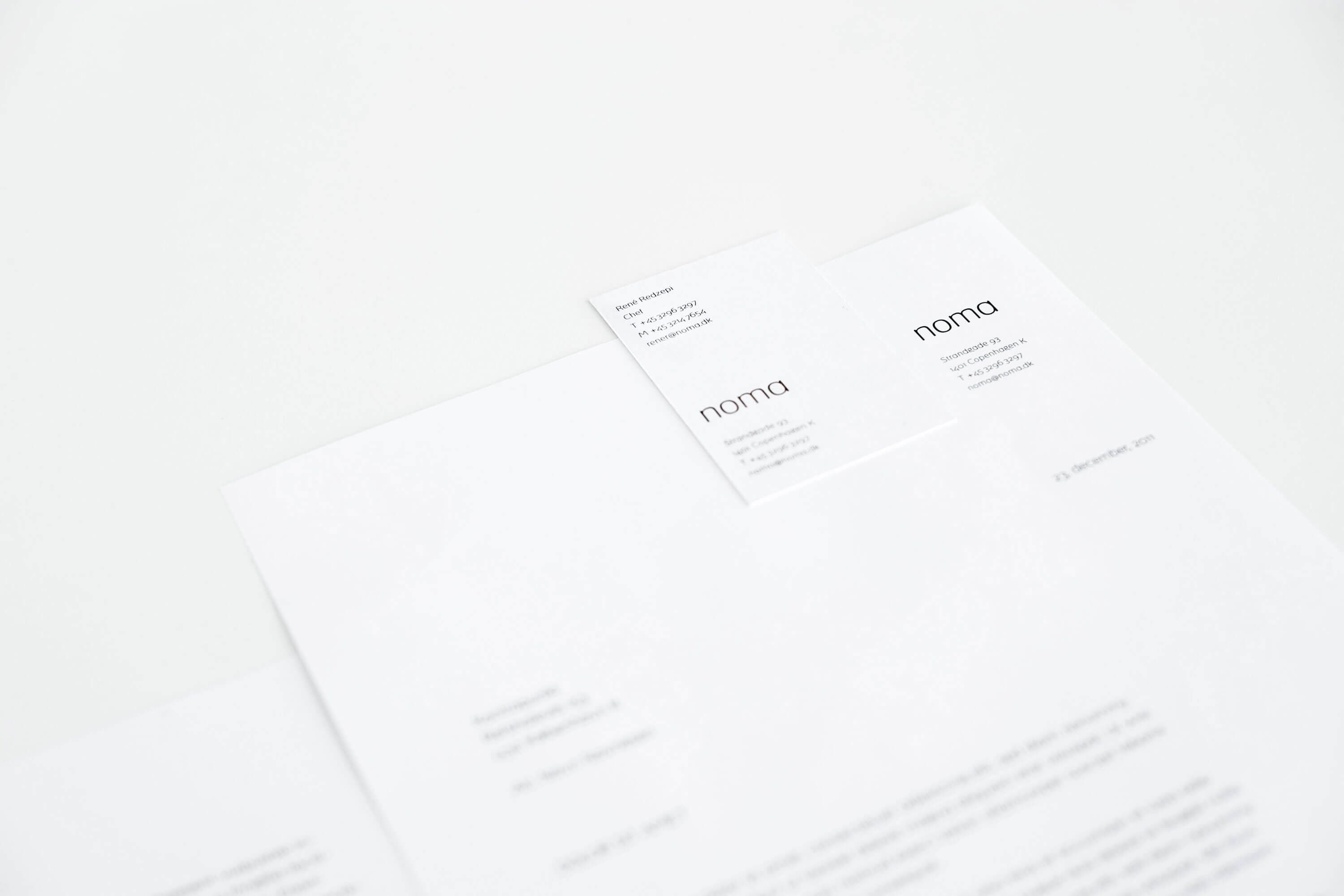white letter and white business card with black bespoke 'noma' typeface