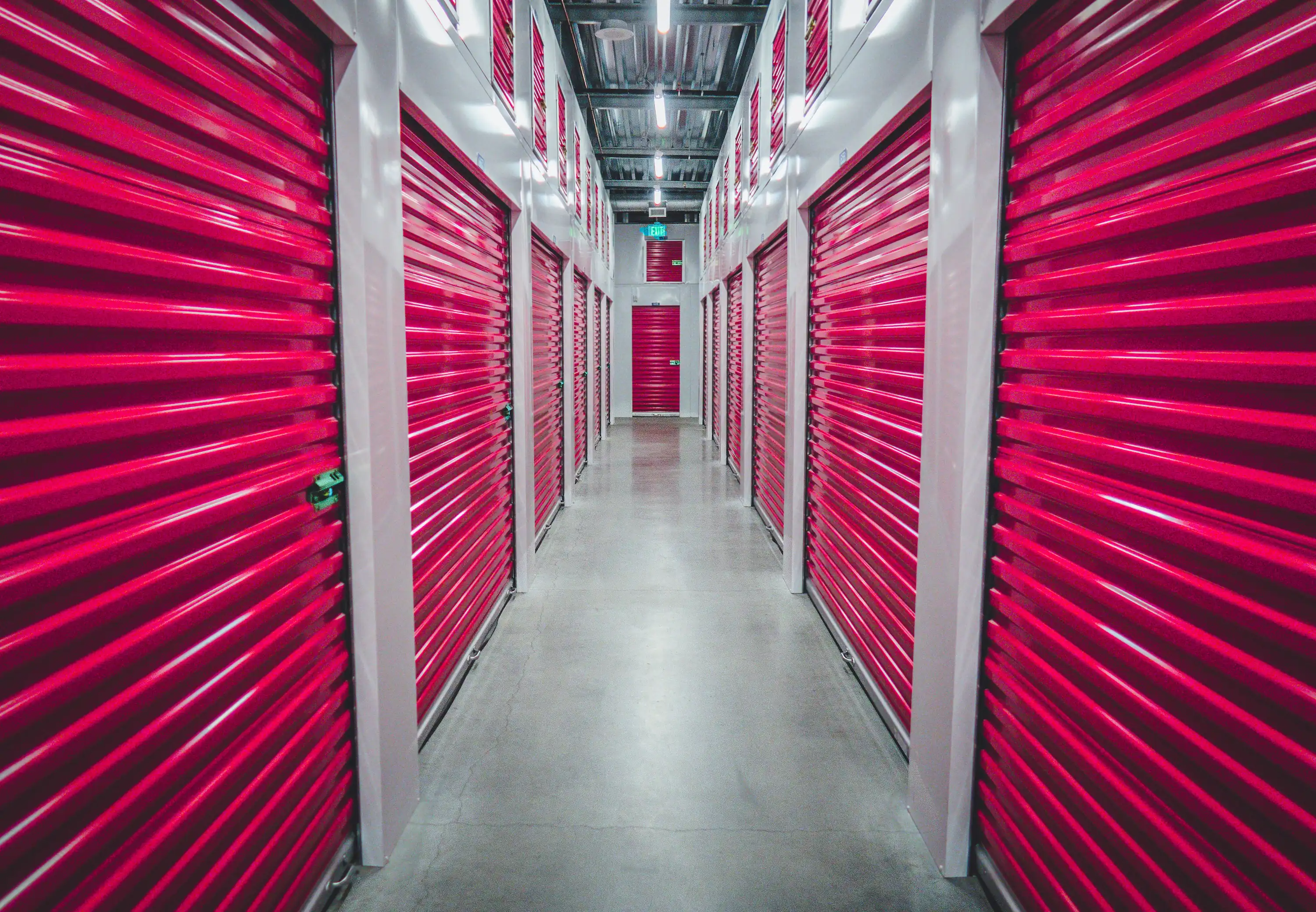 Empty corridor of a self-storage facility with cherry red roller doors