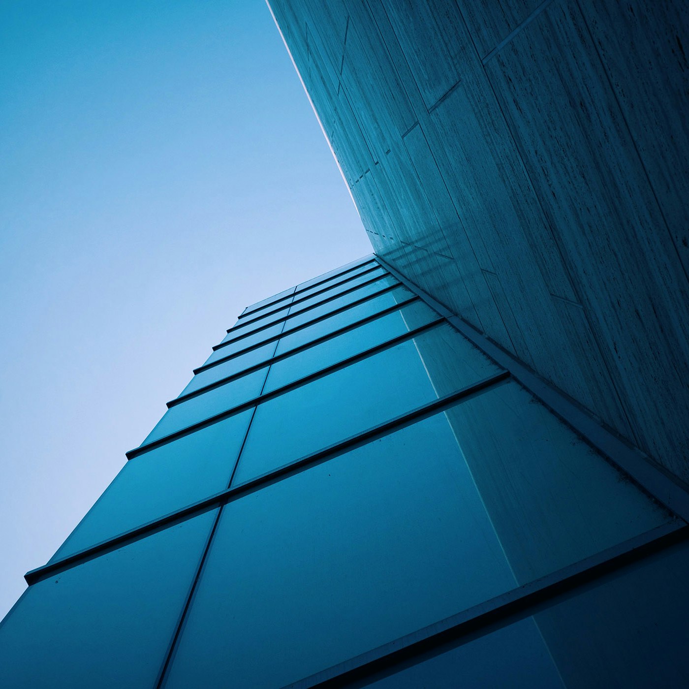 A high building with big glass windows which are reflecting the sky