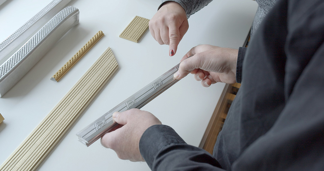 Finger pointing at a z.truded® profile with more profiles on a table