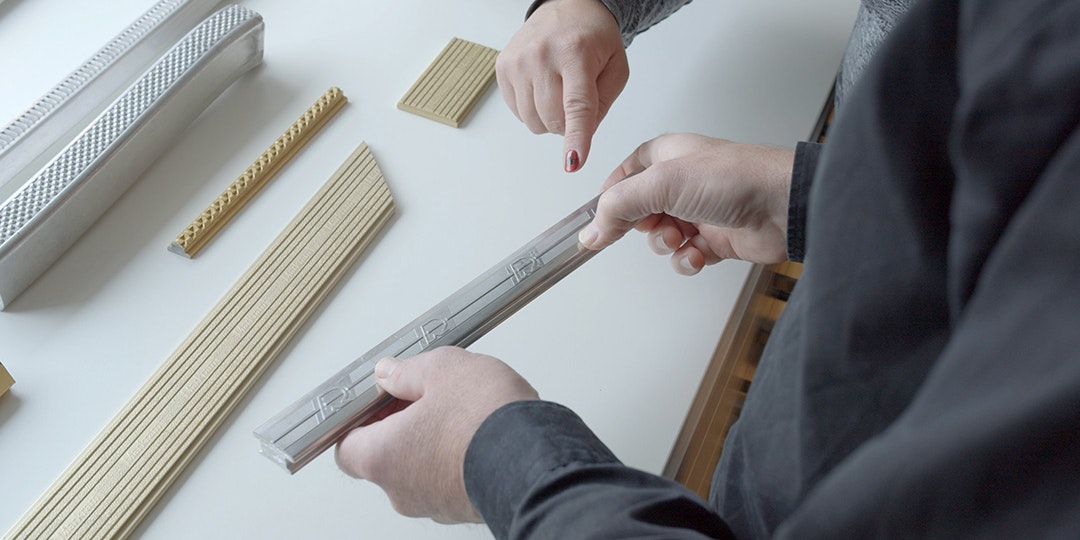 Finger pointing at a z.truded® profile with more profiles on a table