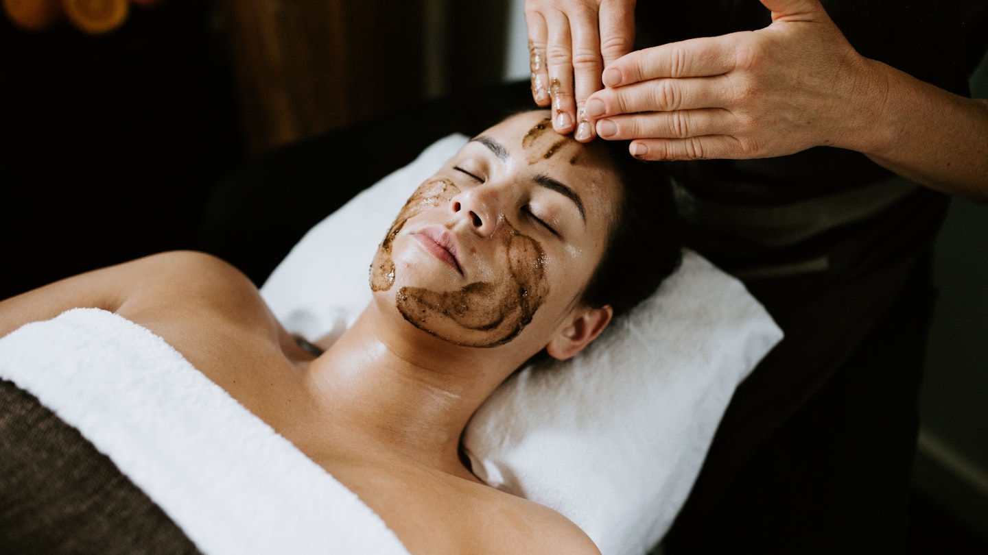 Woman lying on bed getting a face massage
