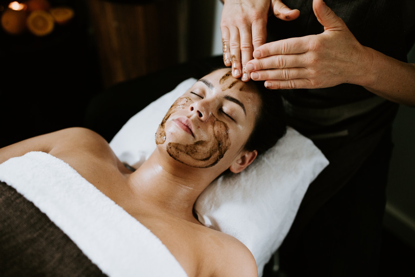 Woman lying on bed getting a face massage