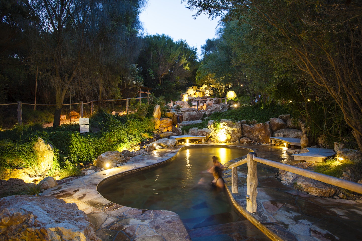 wide shot of bath house pools in the bathing gully at night with view of two people bathing