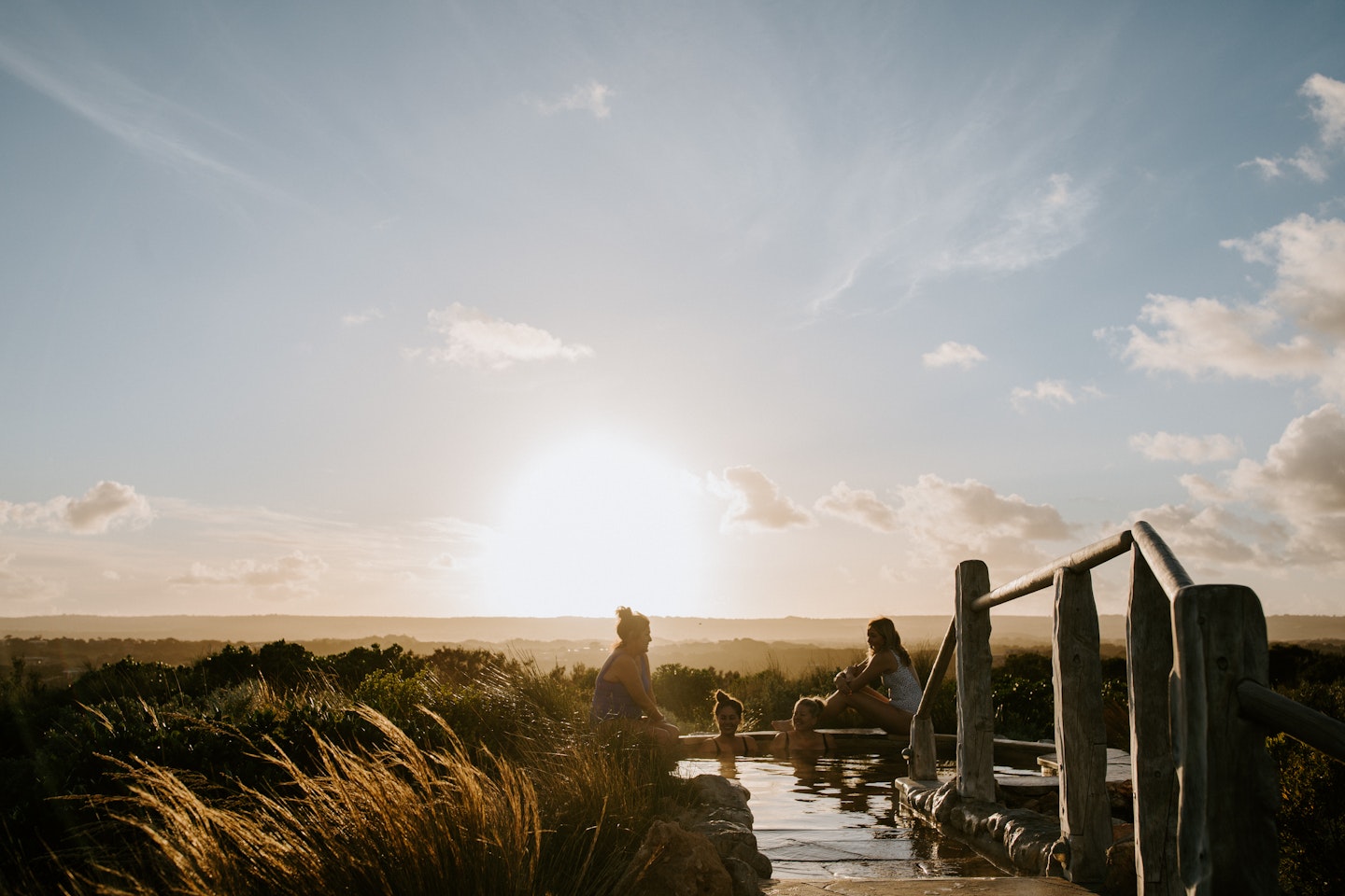 women bathing in hilltop pool as the sun rises 