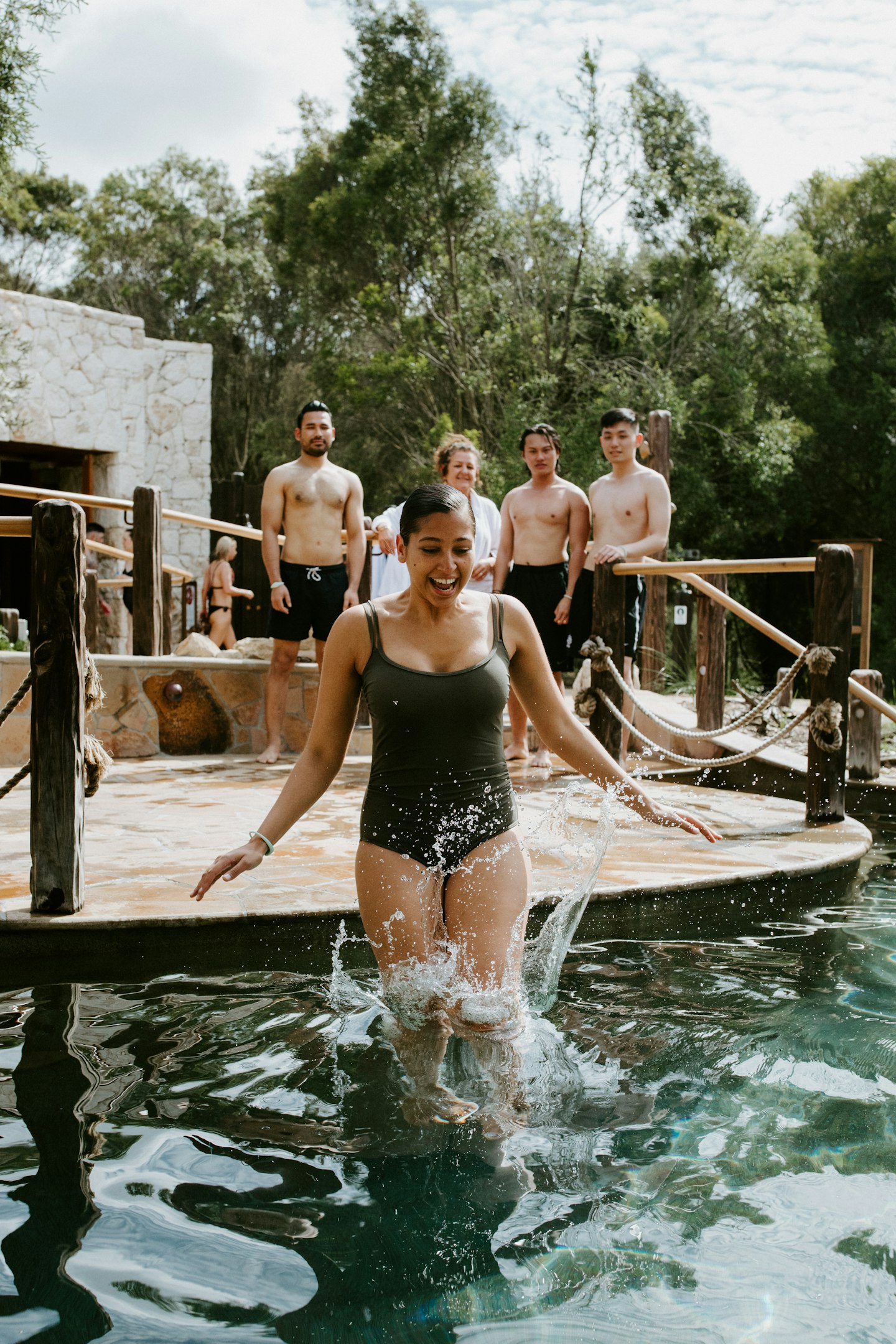 A woman in black bathers diving into the cold plunge pool