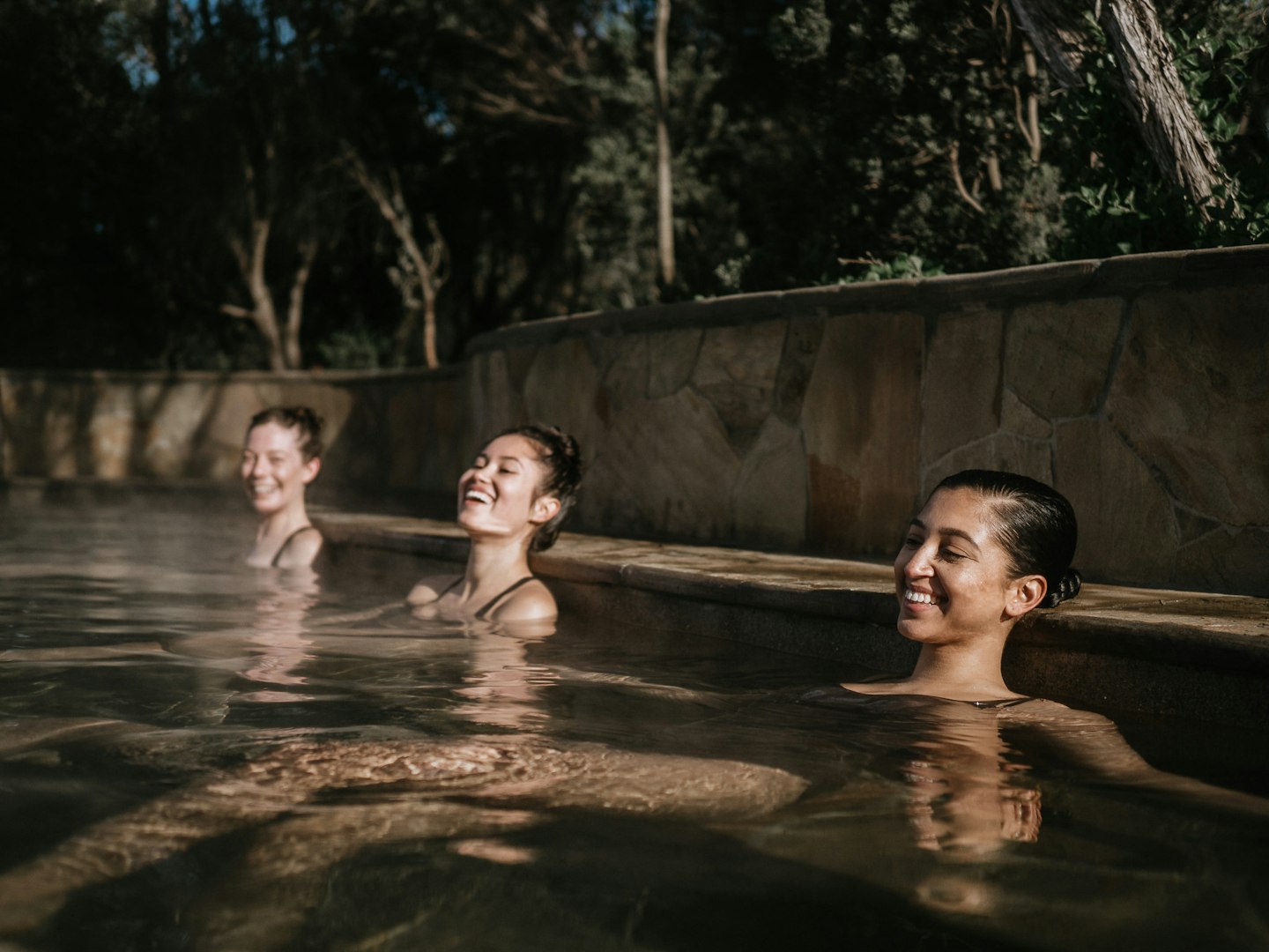 three ladies smiling and relaxing in geothermal pool