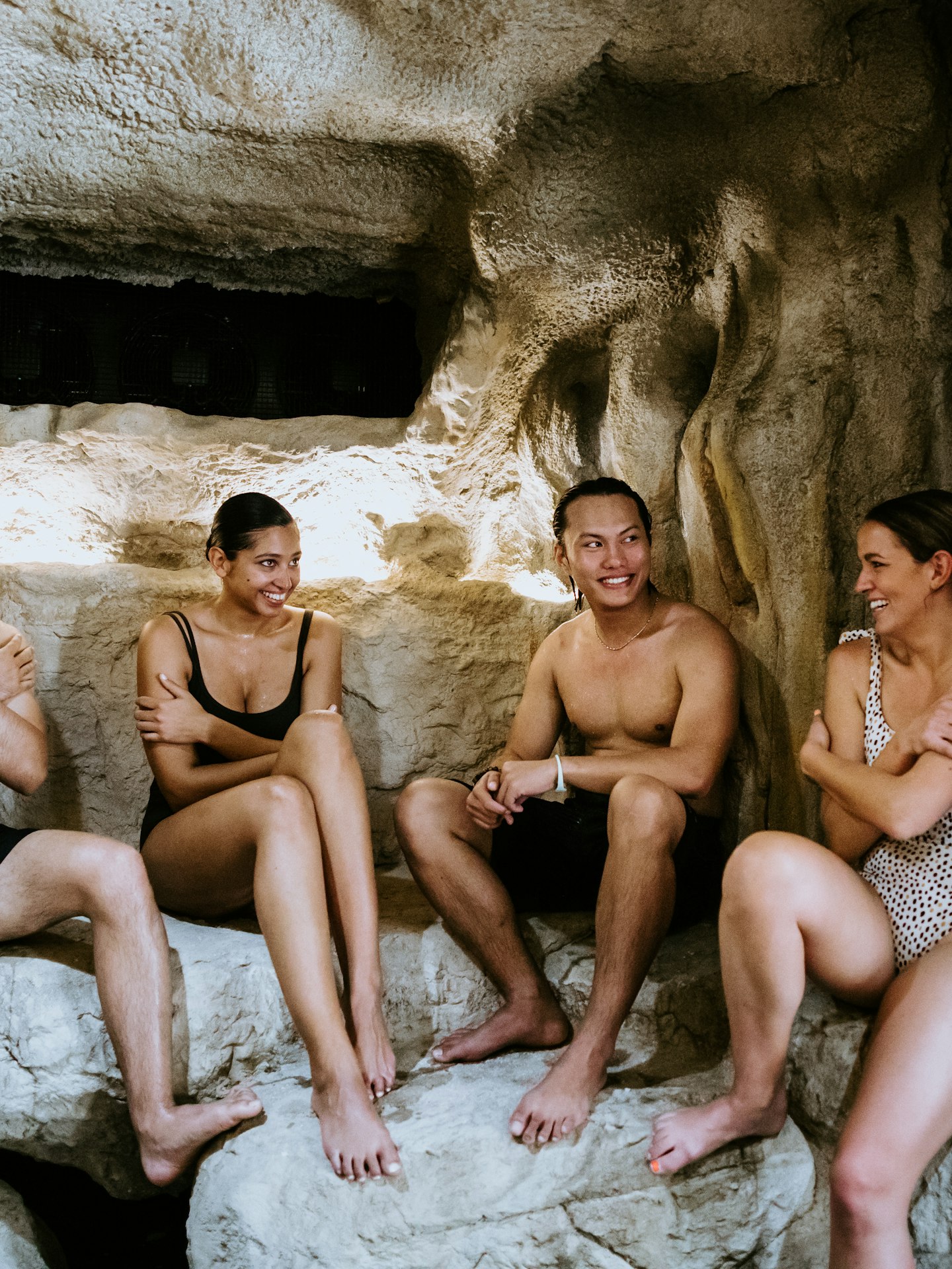 four people in bathing suits sitting in ice cave