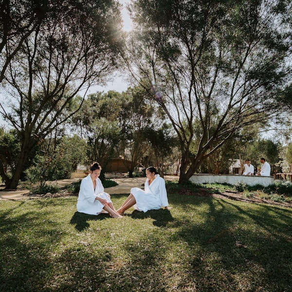 two ladies in robes sitting on grass in natural surrounds
