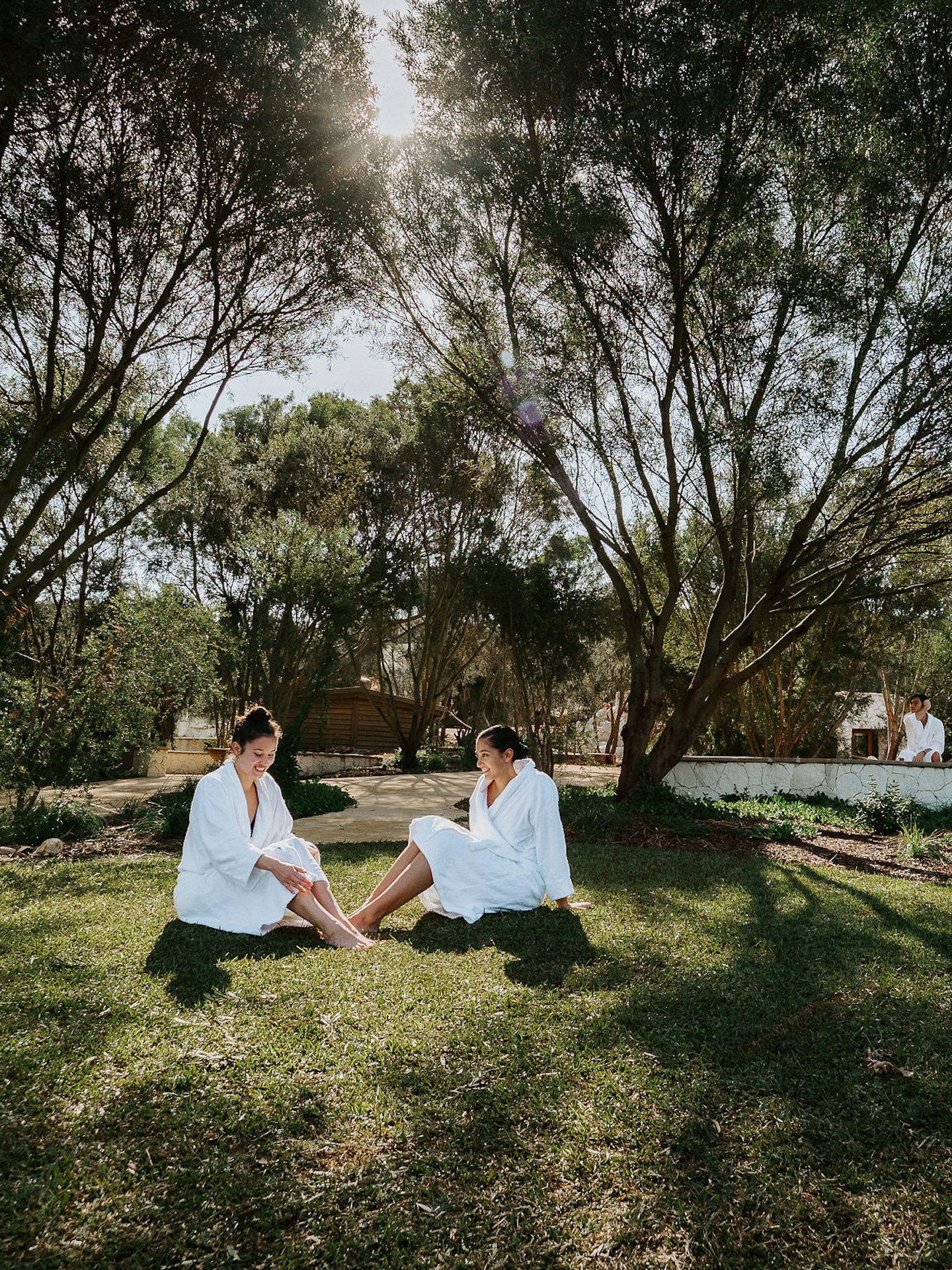 two ladies in robes sitting on grass in natural surrounds