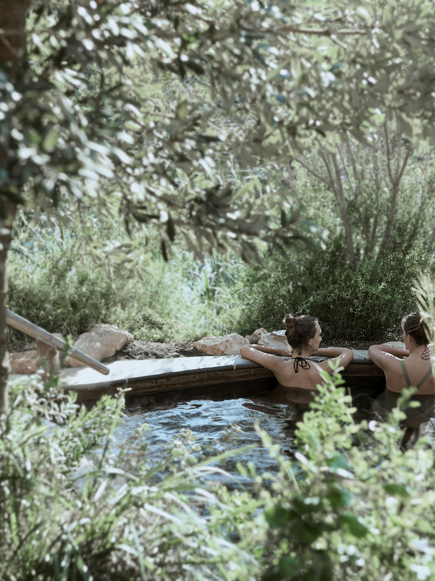 two women in hot pool surrounded by nature