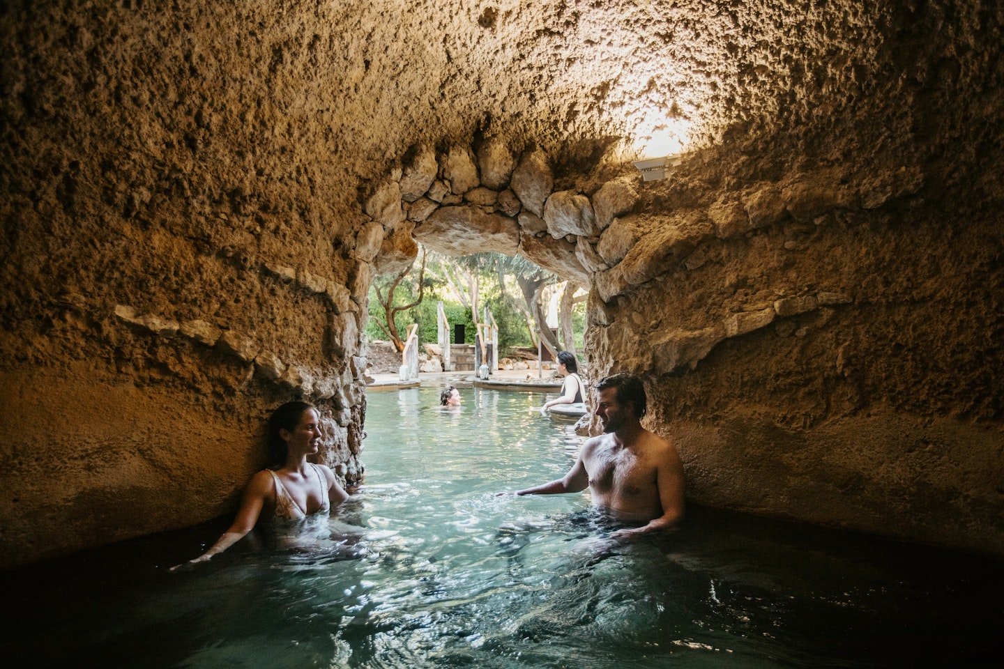 man and woman sitting in cave pool