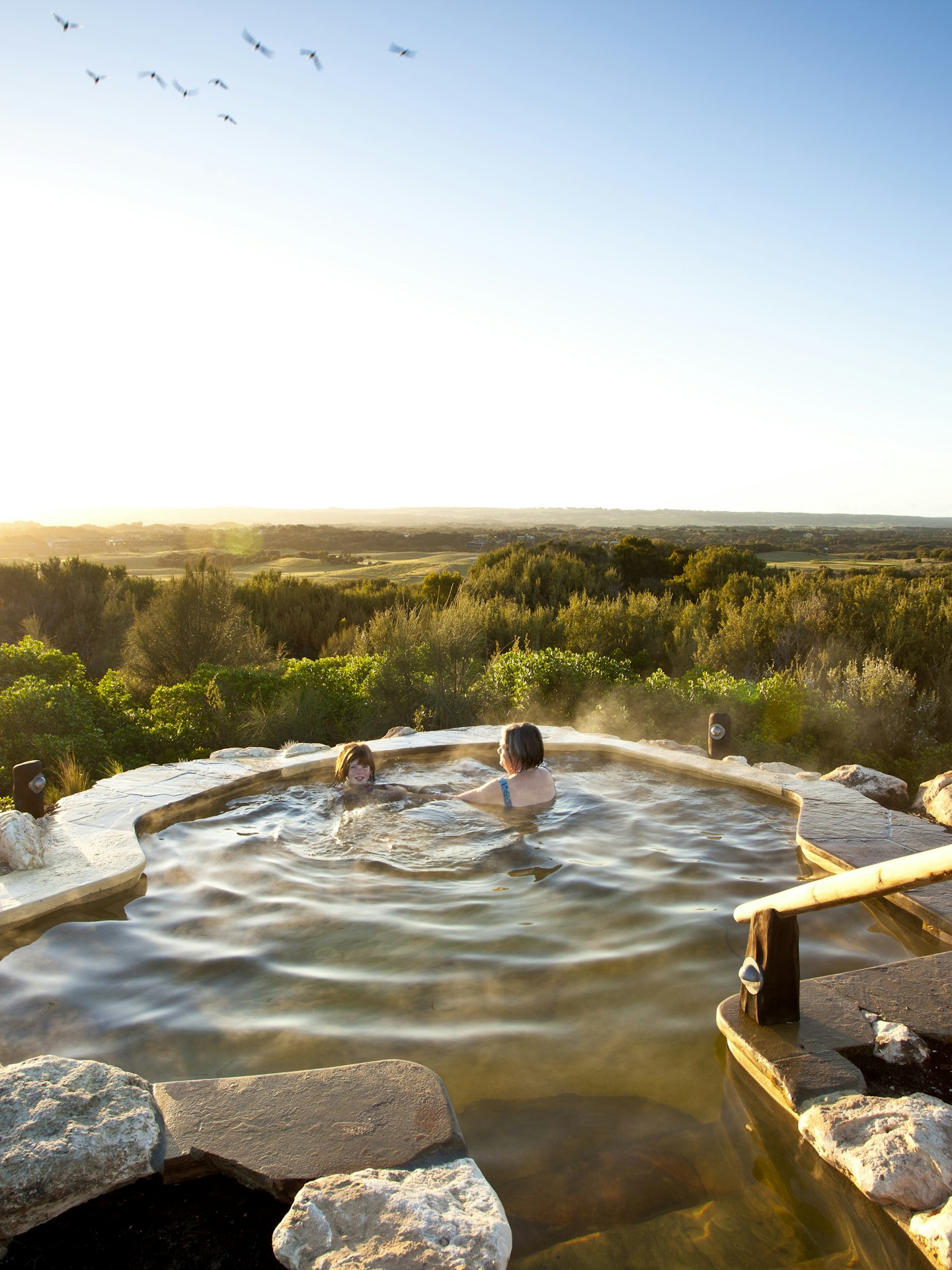two ladies enjoying sunrise in hilltop pool with stunning 360 degree views