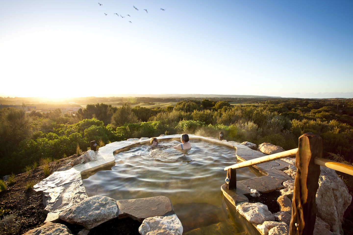 two ladies enjoying sunrise in hilltop pool with stunning 360 degree views