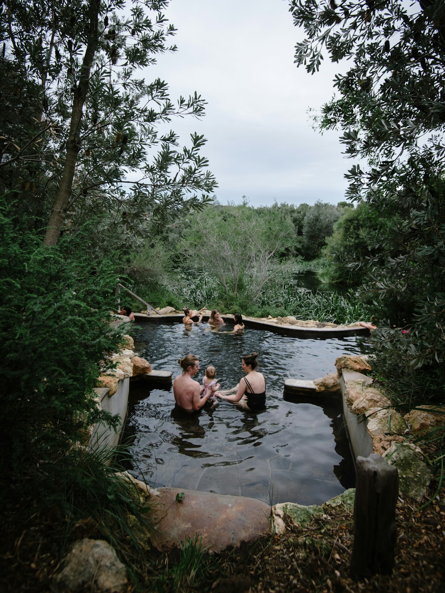 families bathing in geothermal pool surrounded by trees