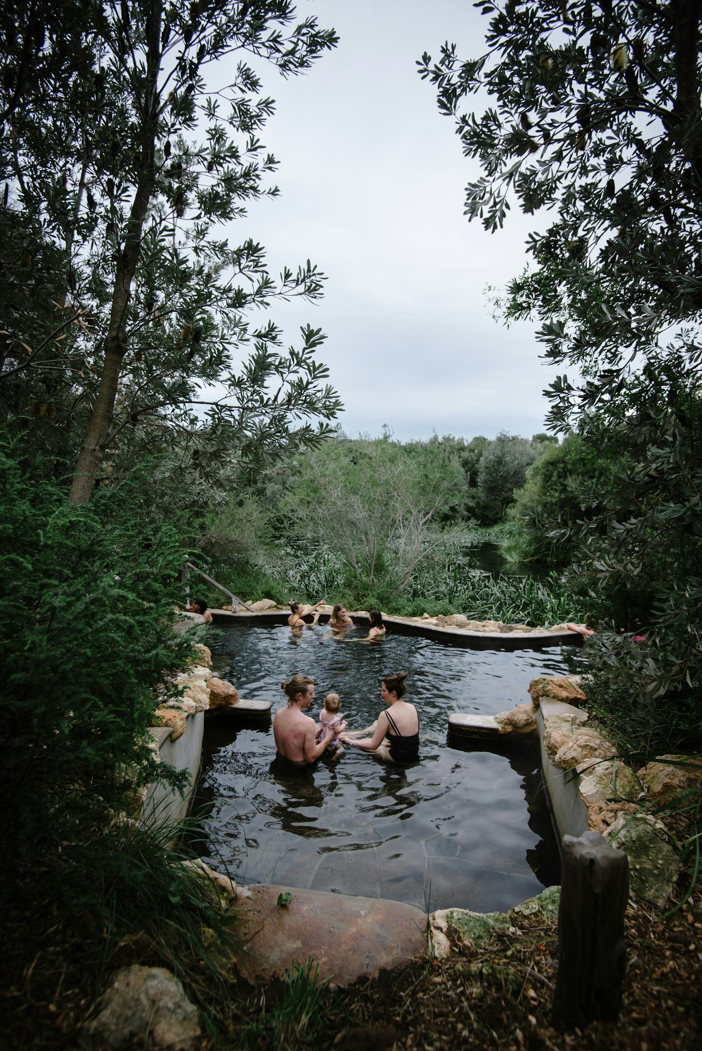 families bathing in geothermal pool surrounded by trees