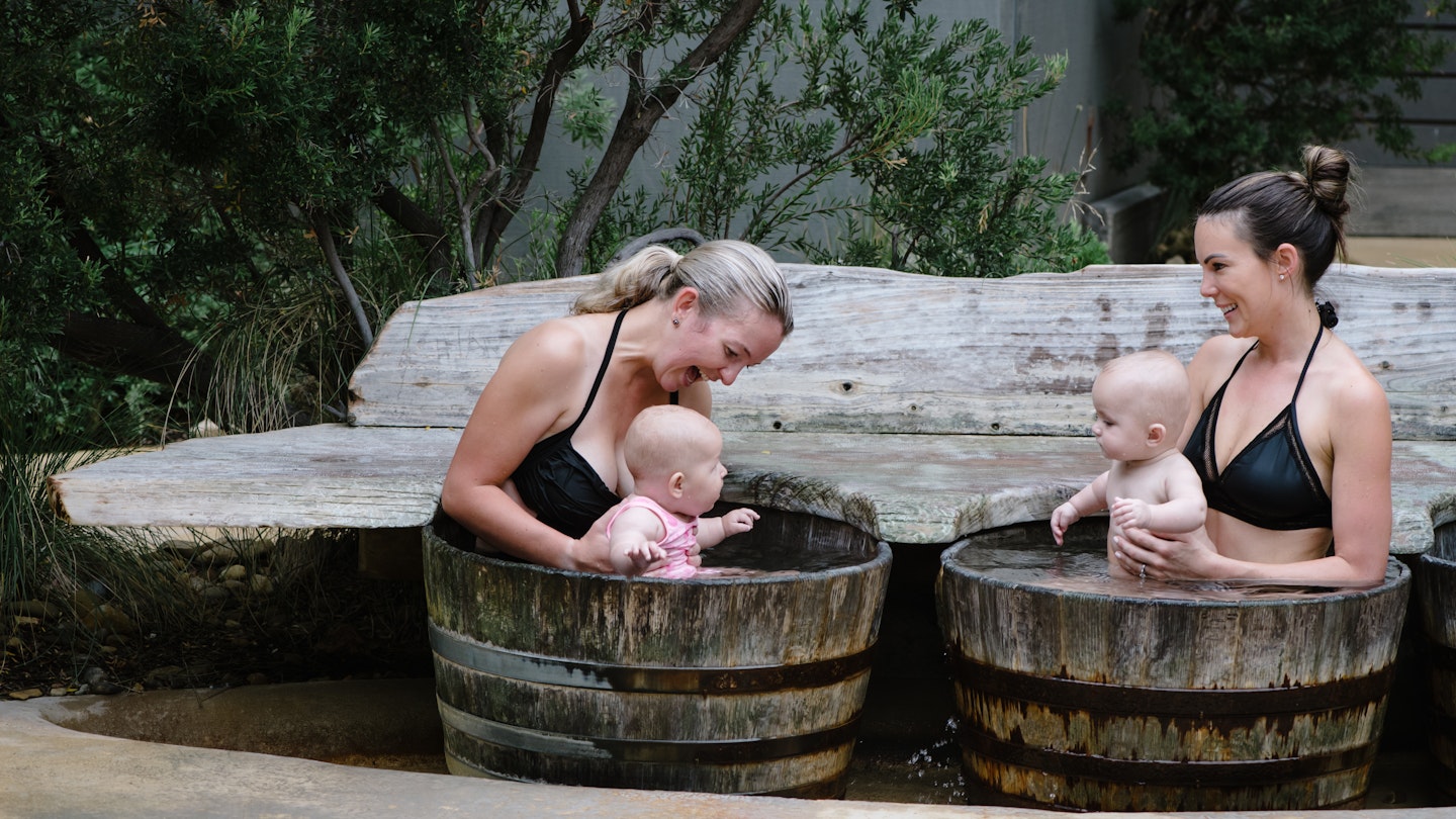 Two women with babies in barrels
